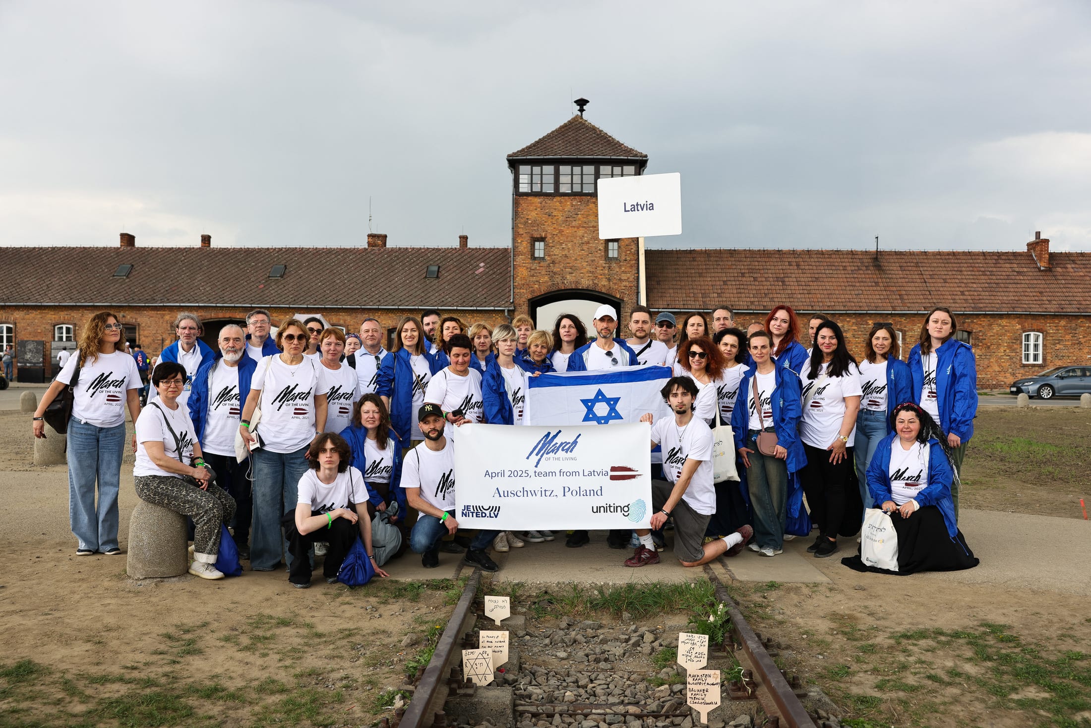 Latvian March of the Living team at Auschwitz-Birkenau with delegation banner, April 2025