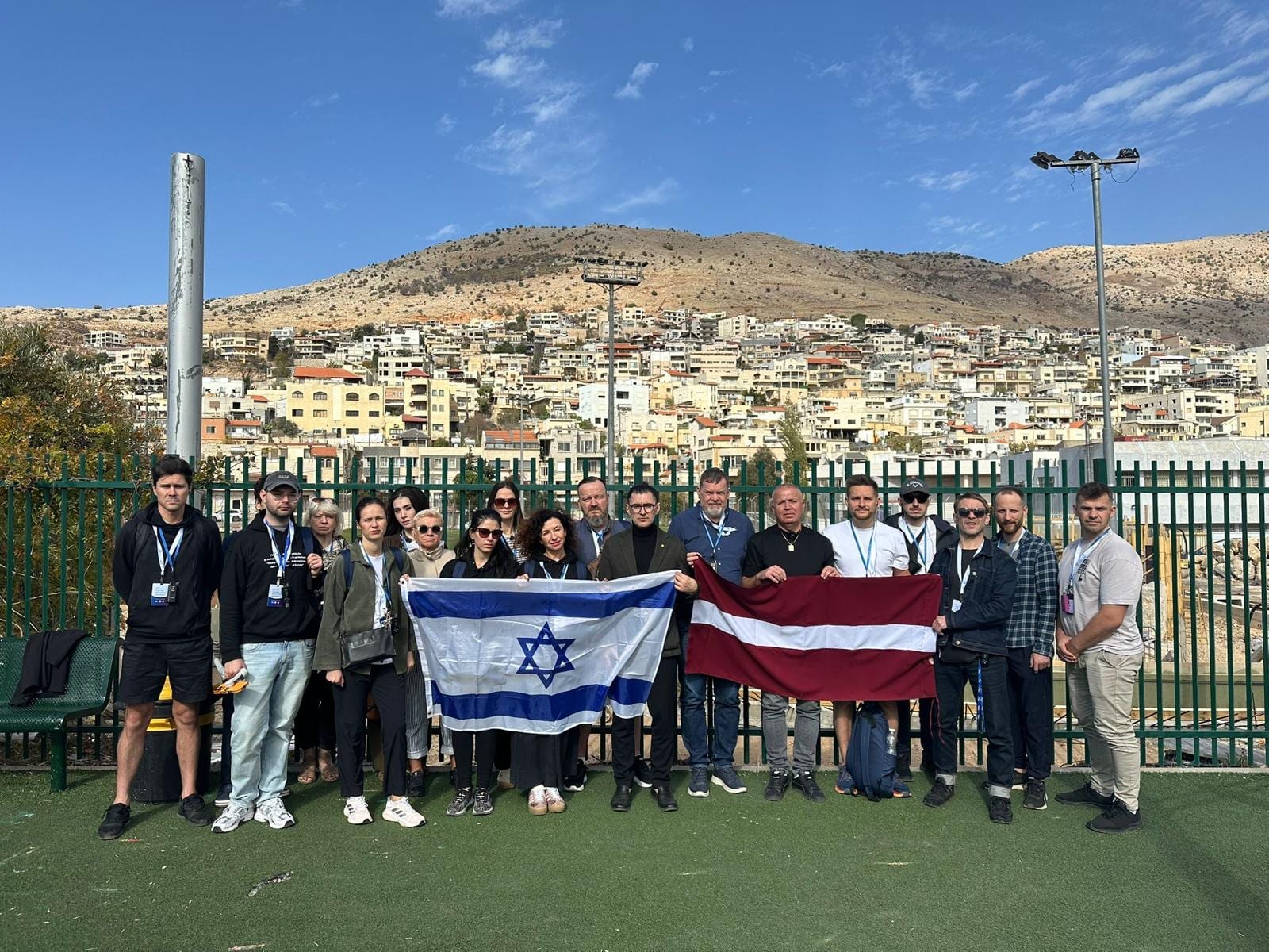 JEWNITED.LV delegation with Israeli and Latvian flags overlooking a hillside town