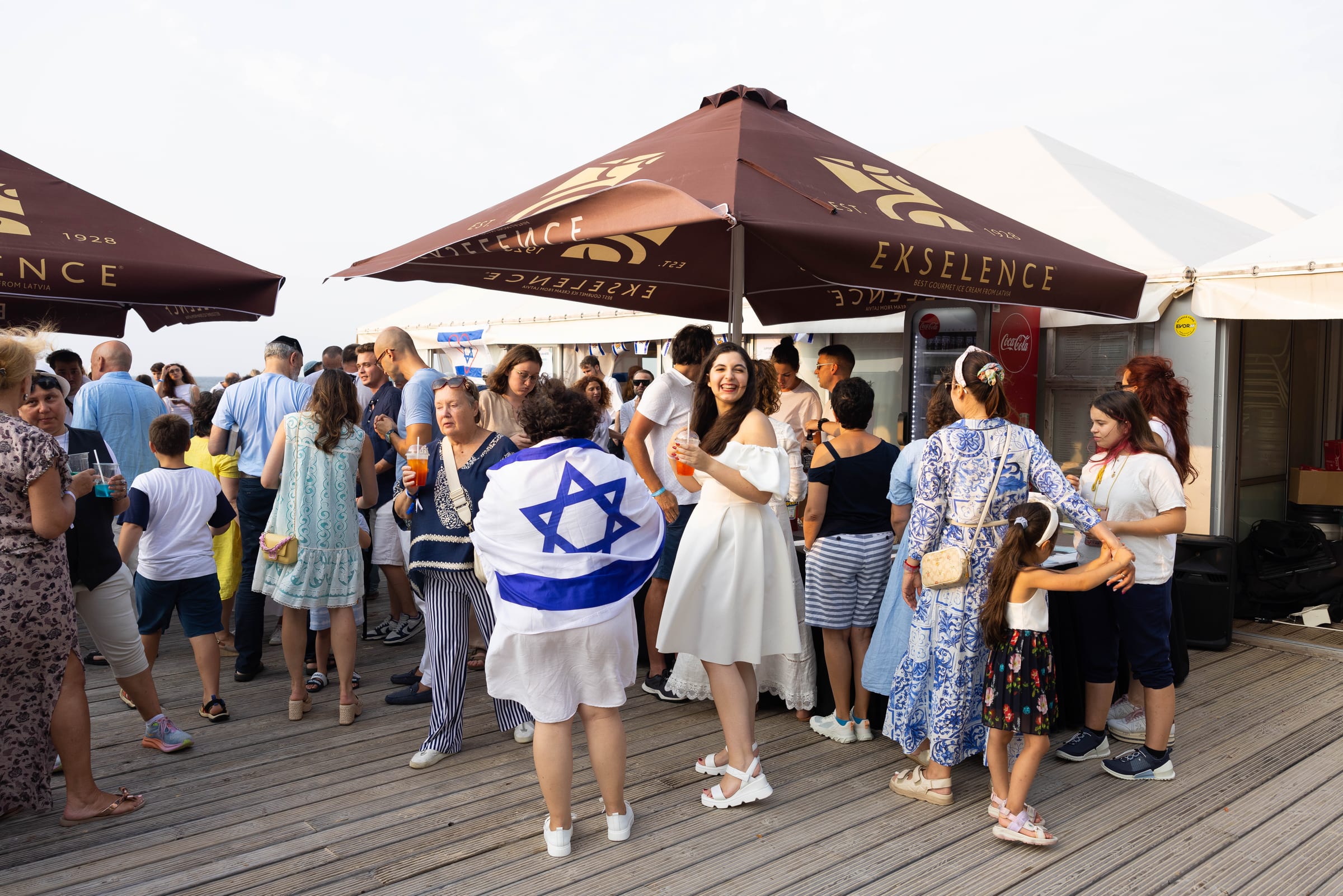 Outdoor Nova tribute gathering on a deck with Israeli flags